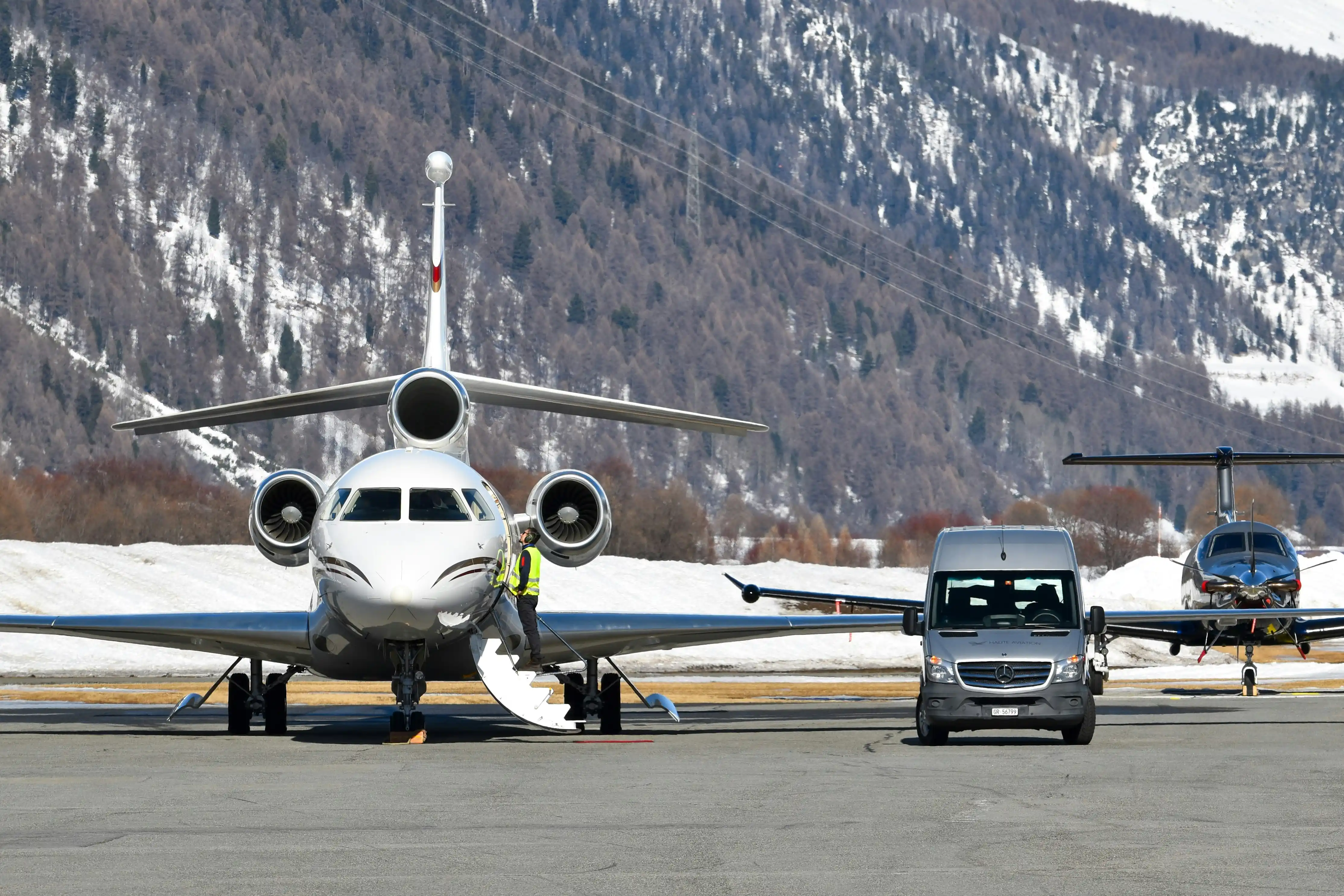 Split-screen airport pickup scene showing a private black SUV with a chauffeur on one side and passengers boarding a shared shuttle van on the other